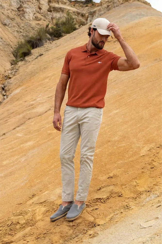 Hombre con camiseta polo terracota, pantalón de algodón beige y gorra beige de Salvador Beachwear